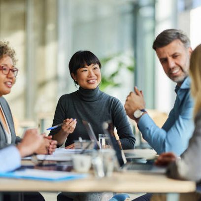 Group of happy multiracial entrepreneurs communicating during a meeting in the office. Focus is on Japanese woman.